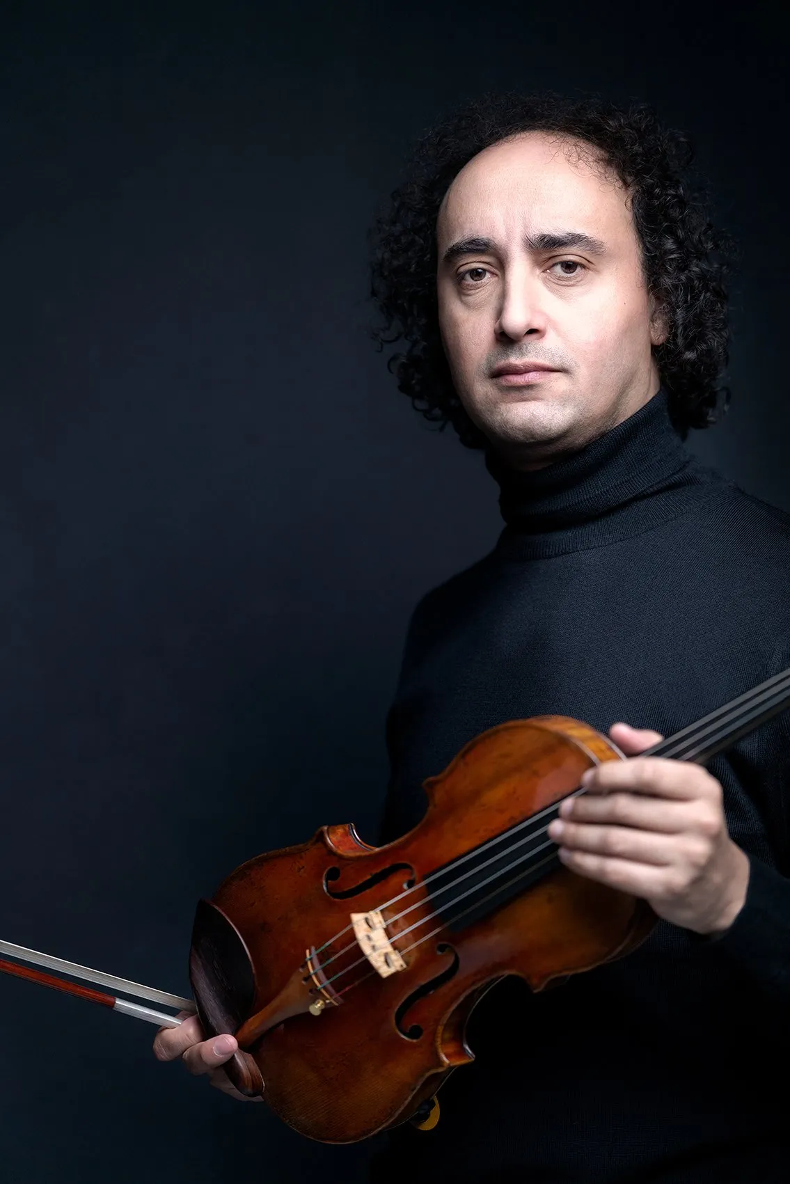 Mario Hossen holding his violin, studio portrait